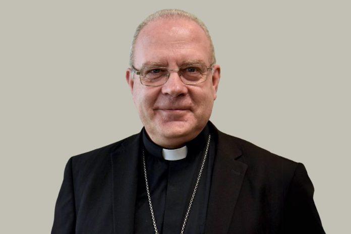 A priest wearing a black suit and glasses, exuding a sense of authority and professionalism in a solemn setting